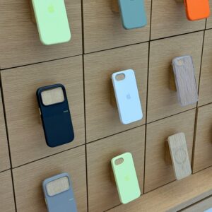 A variety of colorful phone cases displayed on a sleek wooden wall in a store.